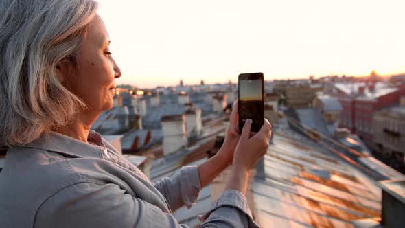 Grey-haired Female Tourist Making Photos on Roof