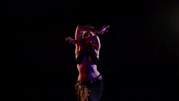 A Woman Who Dances an Oriental Dance on a Black Background in the Studio Makes Beautiful Movements