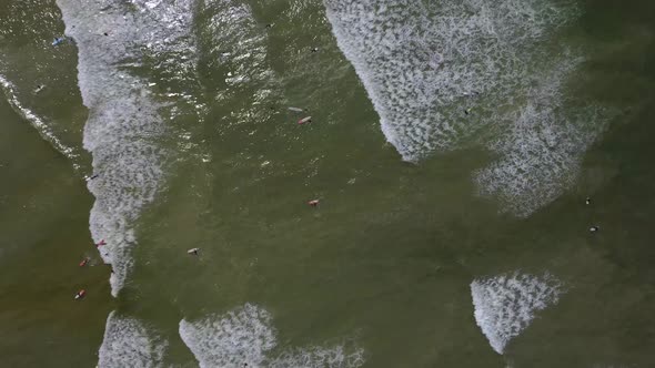 Birds eye drone shot of surfers at Muizenberg beach, Cape Town - docents of surfers trying to catch