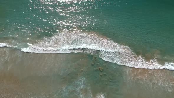 Aerial of front of the beach, waves hitting the sand