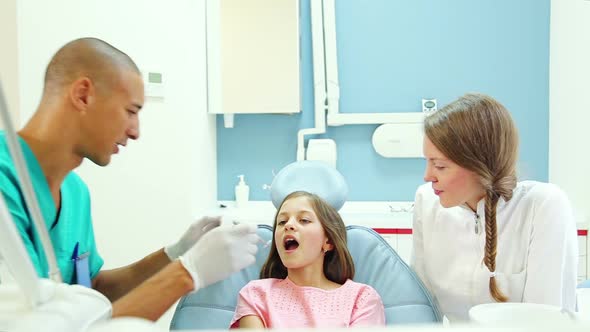 male dental surgeon doing routine dental check up to lovely little girl