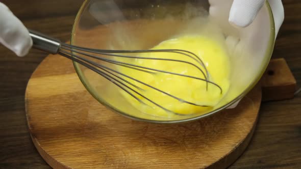 Person preparing homemade omelette mixing with whisk eggs. Close up. HD