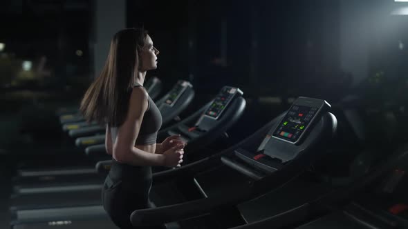Ypung Female Athlete Run on a Treadmill Aerobic Exercise and Endurance Training in the Gym Nightlife