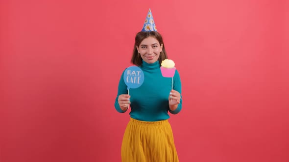 Happy Young Woman in Party Hat Holding Birthday Accessories Over Red Background