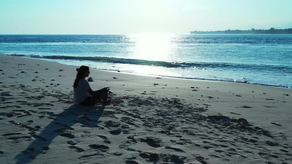 Beautiful smiling ladies on photoshoot in the sun at the beach on clean white sand and blue 4K backg