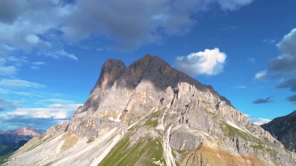 Aerial view orbiting steep Peitlerkofel South Tyrol Dolomites rocky mountain summit against blue clo