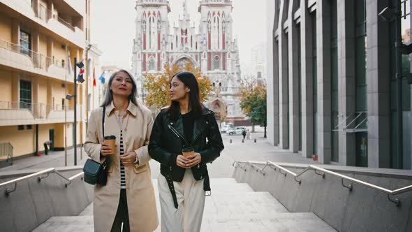 Asian Middleaged Woman and Her Adult Daughter Smiling Talking Walking Up Stairs Leading to a