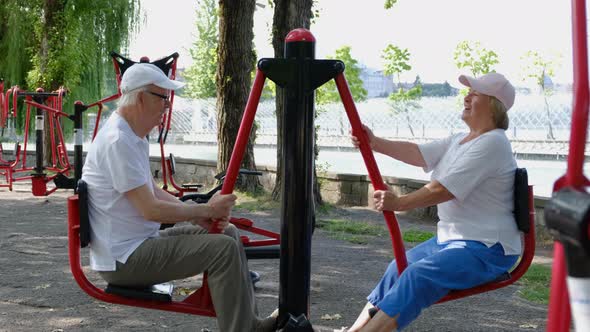 Elderly couple doing sports on the simulator outdoors.