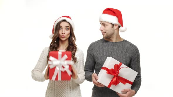  Young Couple Playing and Hiding Behind Christmas Present Box on White Isolated Background