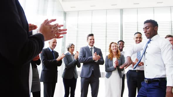 Businessman dancing while his colleagues applauding