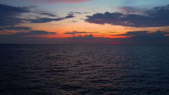 4K drone flying over the sea, sunset on the horizon.