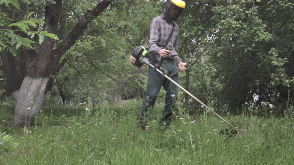 Worker with a gas mower in his hands, mowing grass in front of the house