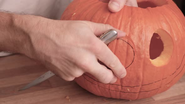 Male Hands Carving Pumpkin Head, Jack O Lanterns, In The Kitchen For Halloween Preparation. - Close