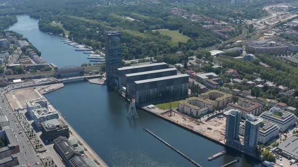 Aerial Footage of Molecule Man Sculpture on Spree River in From of Treptower Tall Building Complex