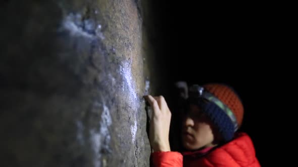 Detail of a mans hands as he climbs boulders at night.