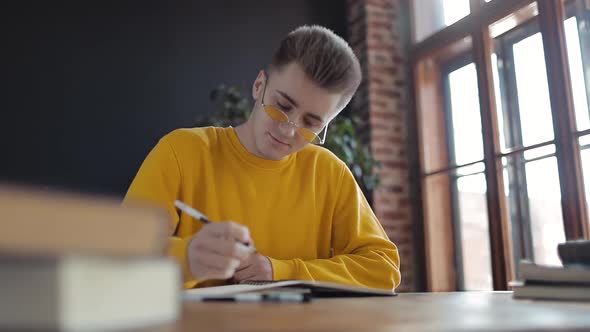 Young Student Thinking and Writing in Notebook