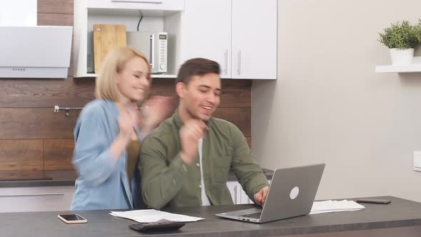 Happy Excited Married Couple Uses Laptop To File Mortgage Documents.