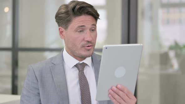 Video Call on Tablet by Middle Aged Man in Office