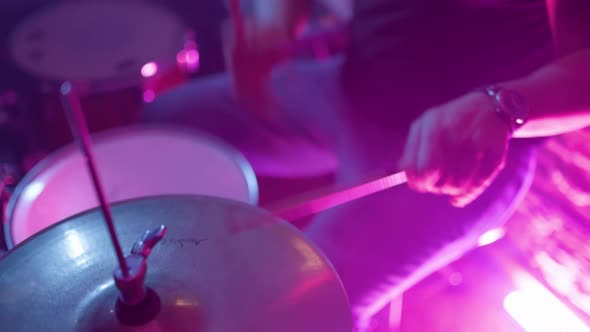 Young musician faceless drummer playing drums with drumsticks