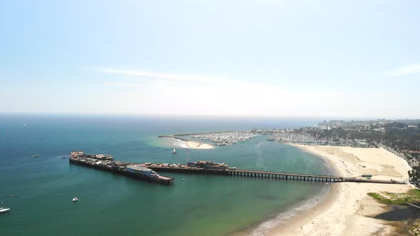 Aerial drone shot over Stearn's Wharf pier and the blue ocean harbor full of sail boats in Santa Bar