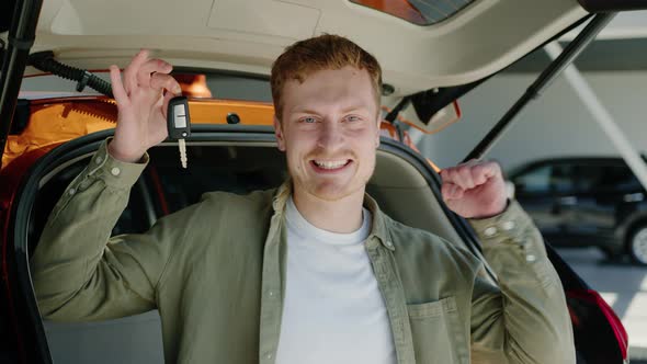 Portrait of a Joyful Man Who is Sitting in a New Car with a Key