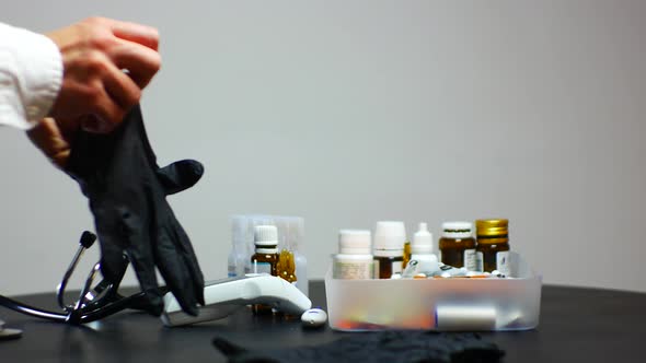 Doctor putting on black gloves to start patient examination with stethoscope and electronic thermome