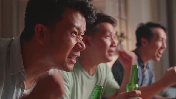 Three Asian Males Cheering And Watching Football Game On Tv And Celebrating Victory At Home