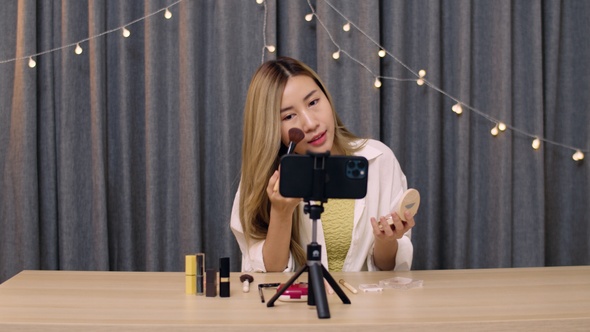 Asian woman beauty blogger influencer makeup artist recording on smartphone educational.