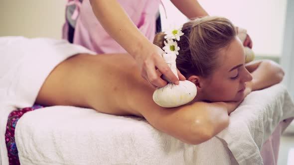 Massage Therapist Using Herbal Compress on Woman