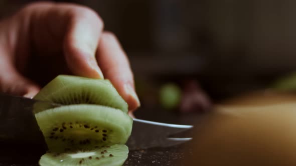 Slicing a Juicy Green Kiwi on a Black Marble Cutting Board