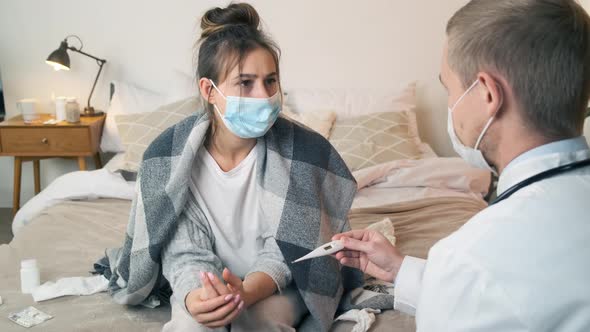 Doctor Measuring Temperature of Young Woman in Medical Mask with Thermometer