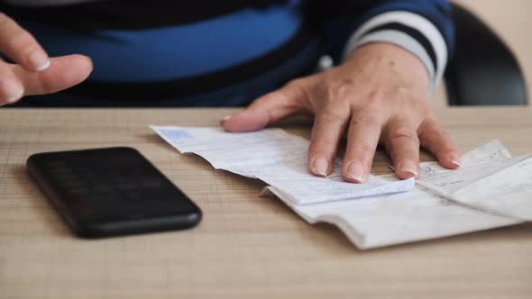 Count a Family Budget. Female Count Utility Services Bill on the Telephone By the Table.