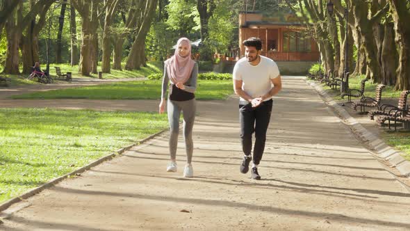 Happy Arabian Couple in Activewear Jogging at Green Park During Morning Time