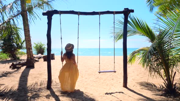 Woman with Hat Enjoying Freedom on Swing in Phuket Thailand