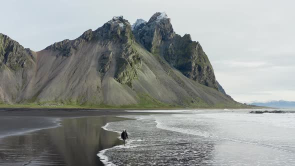 Drone Of Man Walking On Black Beach From Vestrahorn Mountain