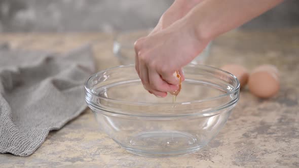 Female Hands Breaking an Egg and Separating Yolk From White