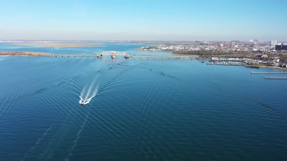 An aerial shot over Grassy Bay in Queens, NY. The camera dolly in & pan left over a boat approaching