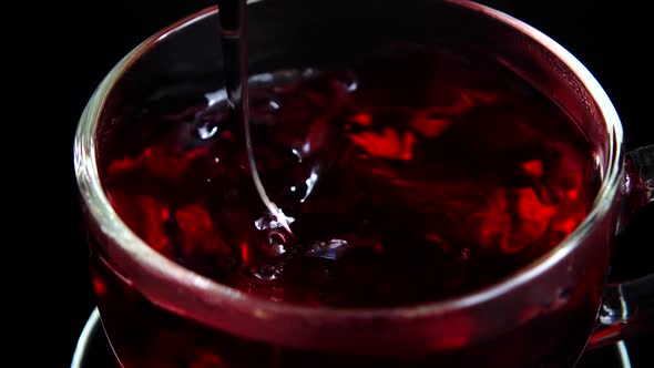 Preparation of Hibiscus tea in a glass cup.