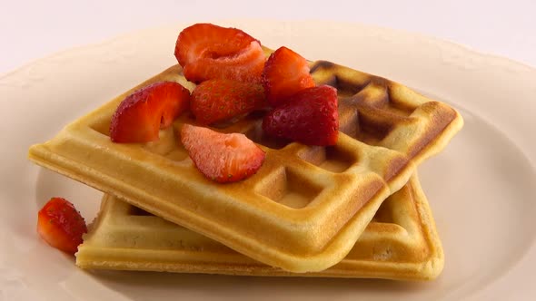 Belgian waffles with strawberry on a plate on a white background.