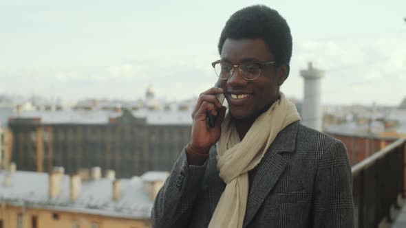 Afro Businessman Walking on Rooftop Terrace and Speaking on Phone