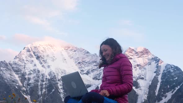 Young Happy Freelance Woman in the Mountains Calls Up Her Friends Via Video Link Via a Laptop and