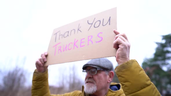 Poster with the Inscription Thank you Truckers in the Hands of an Elderly Man in Winter Clothes and