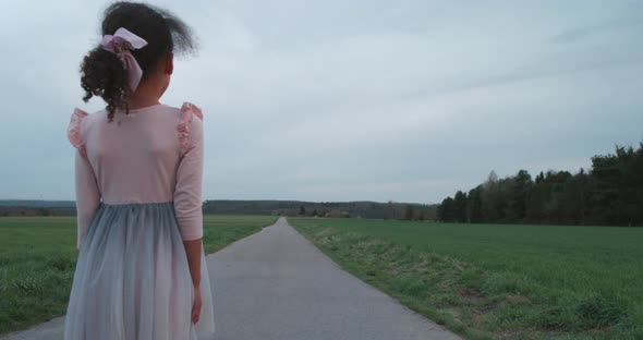 Lost little girl staring down a long empty countryside road