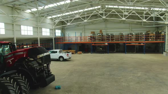 White Truck and a Big Modern Tractor in a Garage for Heavy Machinery