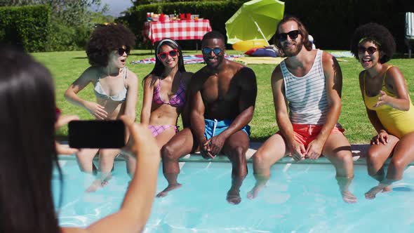 Group of diverse friends posing for a picture while sitting by the pool