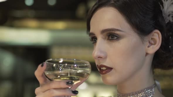 Closeup Portrait of a Young Attractive Woman in a 1920s Style Drink Wine or Champagne at the Bar