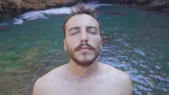 Young man opening his closed eyes at sea.