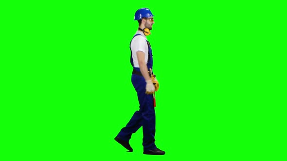 Builder Goes To the Object with a Helmet and Tools. Green Screen. Side View