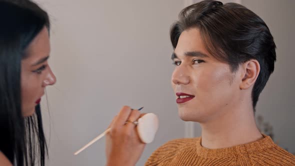 Makeup Studio - Makeup Artist Applying Red Matte Lipstick Over the Pencil on the Lips of Male Model