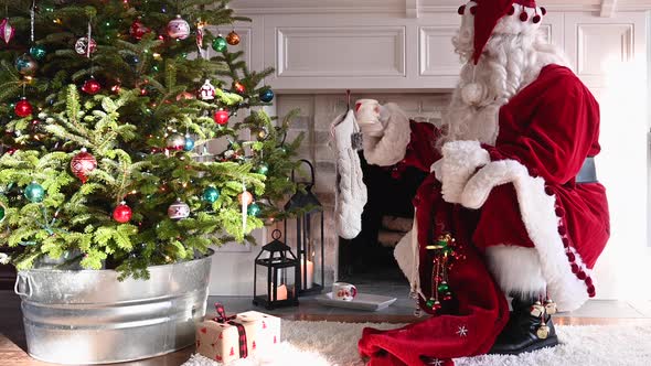 Santa Claus putting gift under Christmas tree